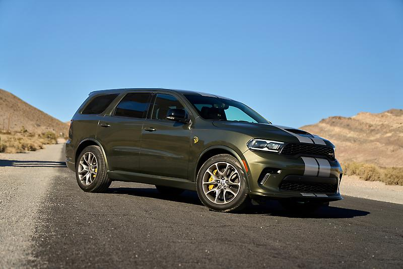 Green Dodge Durango on road with moutains in the background